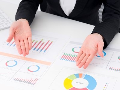 机に広げられた資料の中の該当箇所を両手を広げて指し示す様子