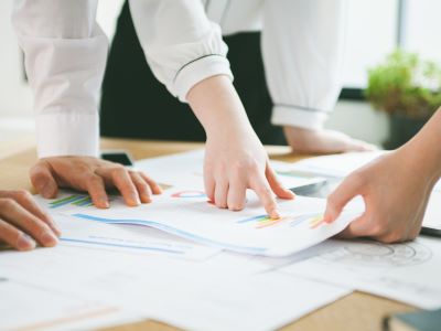 机に広げられた資料の中の一点を指し示す様子