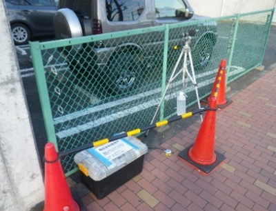 駐車場の近くで機材を用いて測定される様子